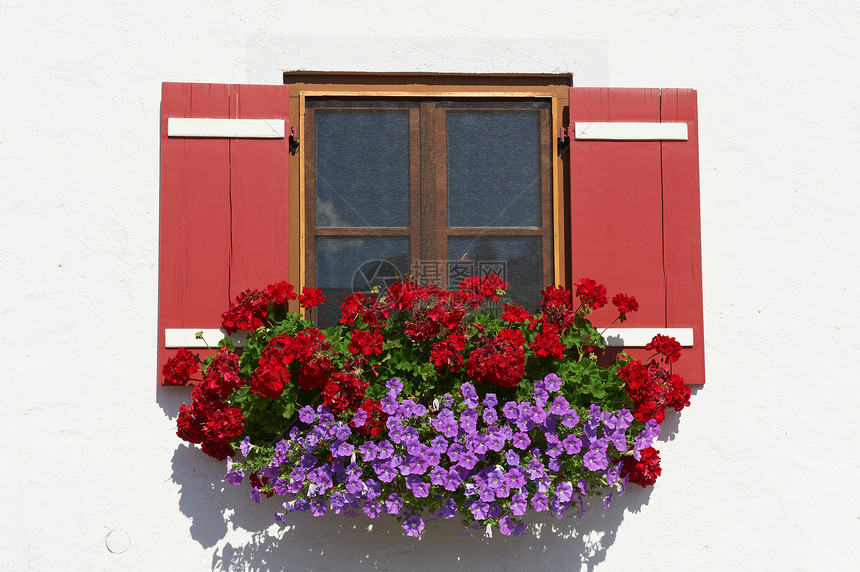 典型的巴伐利亚窗口有开放木制航天器用鲜花装饰图片