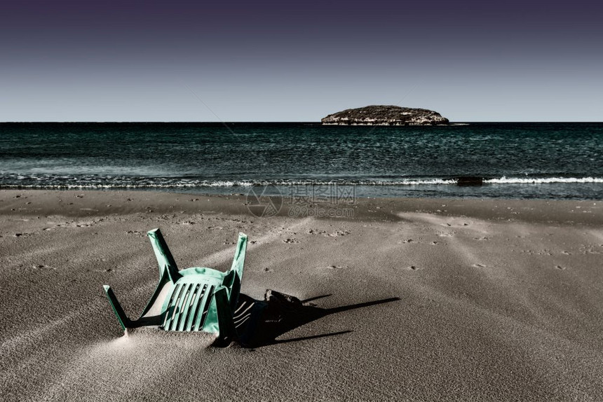 从以色列地中海岸的一个小岛看塑料椅被埋在以色列海滩的沙上图片
