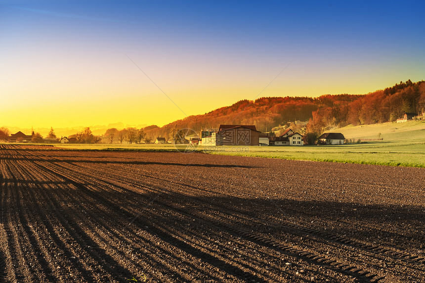 瑞士村庄在日落时被森林和耕种田包围瑞士的农业可耕地和牧场图片