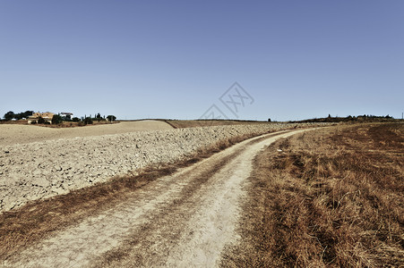 托斯卡纳山丘上的坚固田地收获后的托斯卡纳风景意大利犁田之间的泥土路图片