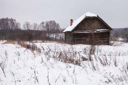 冬季在雪覆盖村庄的废弃农住房图片