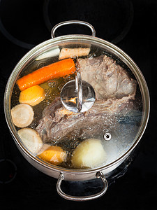 电炖盅煮牛肉汤加蔬菜在玻璃陶瓷锅炉的炖里煮菜背景