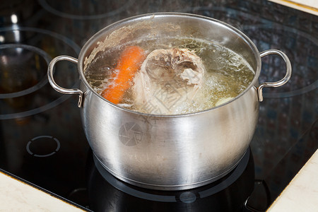 电炖盅用玻璃陶瓷锅炉在钢中调制蔬菜煮鸡汤背景