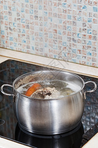 电炖盅在玻璃陶瓷锅炉上用钢里调制蔬菜背景
