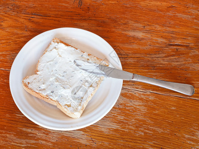 从吐司和软起的三明治和软奶酪的顶部视图和白板上的草药木桌餐刀图片