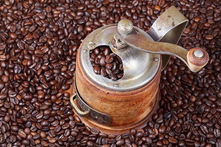 许多烤咖啡豆的老式手工咖啡研磨机图片