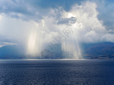 太阳光闪耀在意大利墨西拿海峡沿岸意大利卡拉布里亚海岸线附近的云中图片
