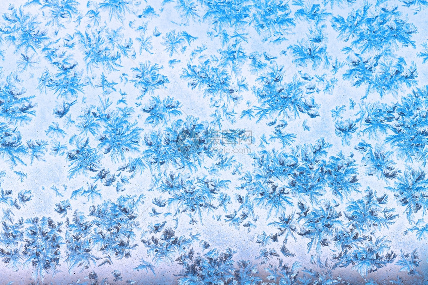 在寒冷的冬天通过雪花和窗上的霜冻模式蓝夜天空的视野图片