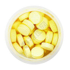 白色背景隔离的圆塑料瓶中黄药片的顶部视图背景图片