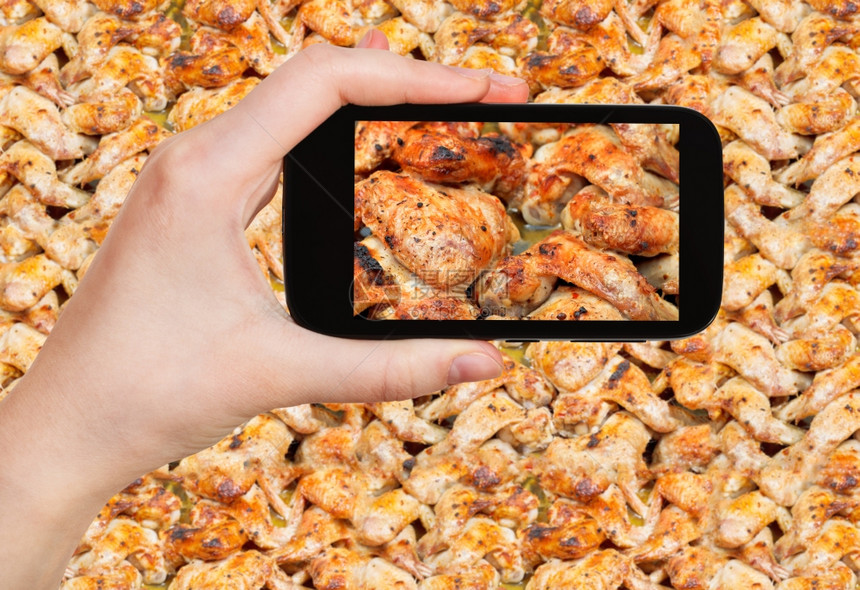摄影食品照片概念旅游者用移动工具在热盘上拍摄烤辣鸡翅膀的照片图片