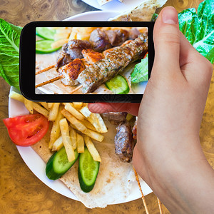 照片食物概念旅游者拍摄移动小工具上混合阿拉伯烤肉串的树枝照片约旦图片