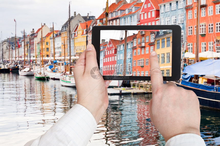 旅行概念在丹麦哥本哈根Nyhavn港区用移动工具拍照的游客图片