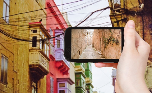 旅行概念在马耳他瓦莱塔的中世纪狭窄街道上用移动工具拍照的游客图片