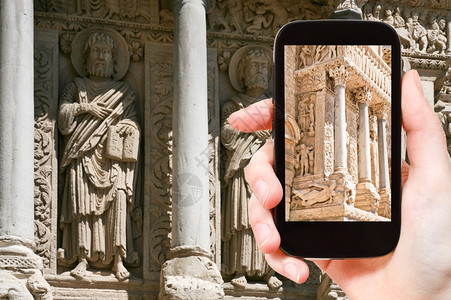 旅行概念游客用智能手机拍摄法国阿尔莱斯圣特罗菲梅教堂马人专栏的照片图片