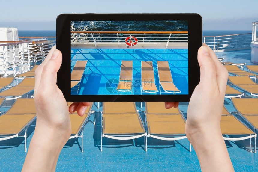 旅行概念游客用智能手机拍摄游轮旁的日光浴椅图片