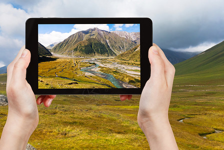 旅行概念旅游者用智能手机拍摄格鲁吉亚Terek河谷高加索山的景象图片