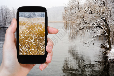 旅行概念游客拍摄美国智能手机冬季下雪时哈德逊河的景象图片
