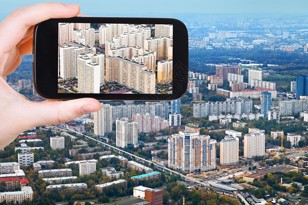 旅行概念旅游者用智能手机拍摄莫斯科秋天现代住宅区图片
