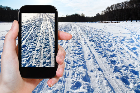 旅行概念游客用智能手机拍摄寒冬冷的雪地滑比赛图片