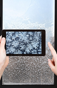 旅行概念游客在冬季寒冷晚上智能手机拍摄窗帘的雪花和霜冻模式图片