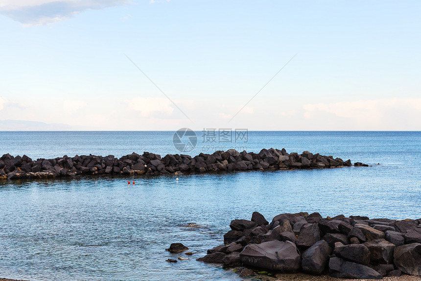 西西里岛爱奥尼亚海贾第迪尼纳克索斯度假村海滩附近的石头防波堤图片