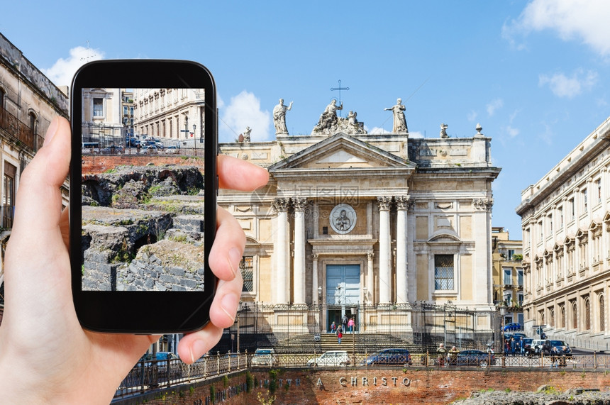 旅游理念游客在智能手机上拍摄古罗马圆形剧场AnfiteatroRomano和圣比亚乔教堂PiazzaStesicoroinCat图片