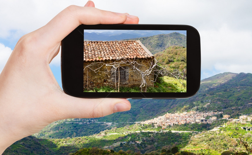 旅行概念旅游者在意大利SicillySavoca村的智能电话春季拍摄山地景观图片