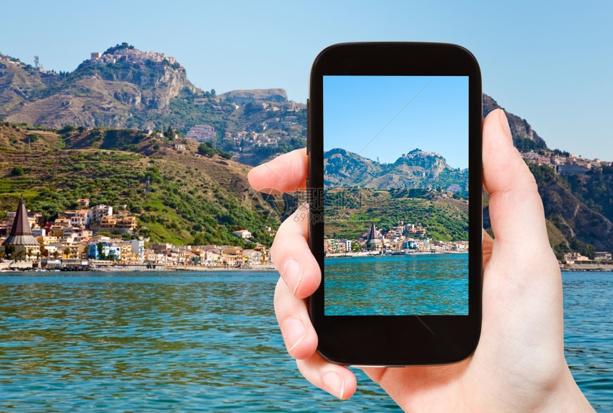 旅游概念旅游者拍摄Taormina山区和西里智能手机上的GardiniNaxos海滩的流行旅游度假胜地Taormina图片