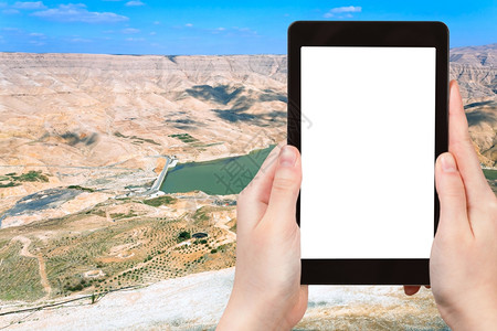 旅行概念约旦AlMujibWadi河和大坝的旅游照片谷点位于约旦平板电脑上有空白广告标志的屏图片