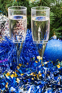 两杯香槟绿色圣诞树背景的蓝色Xma装饰品图片