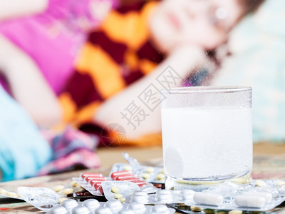 药物溶于水中片在桌上紧闭生病的妇女脖子上围着巾图片