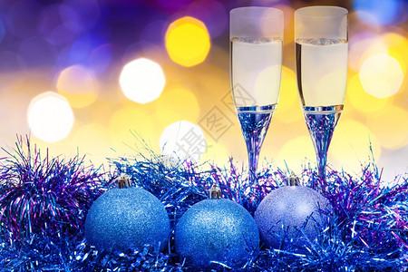圣诞死讯生命两杯香槟和蓝色Xma球黄和紫模糊了圣诞灯布基背景图片