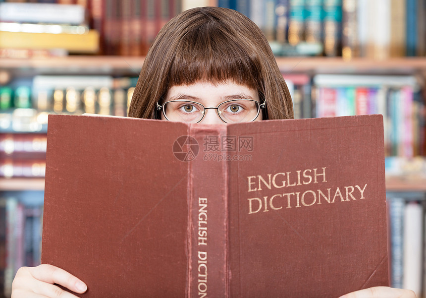 带着眼镜的女孩在图书馆看英文字典本图片