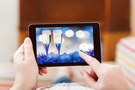 圣诞节概念客厅内的人触摸平板电脑屏幕上含蓝色Xmas死活图片