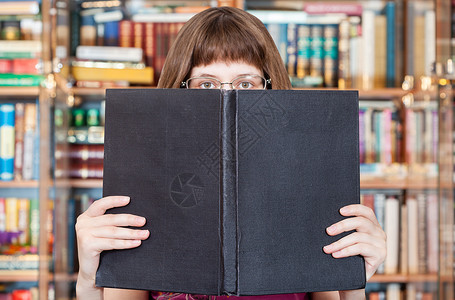 带着眼镜的女孩阅读大书在图馆中空白封面图片