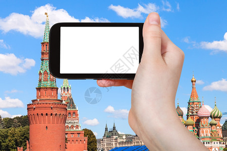 旅行概念手持智能机切断屏幕和莫斯科克里姆林宫红塔的背景图片