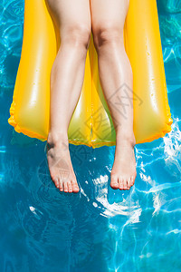 户外游泳池阳光夏日黄气床垫上的女腿图片