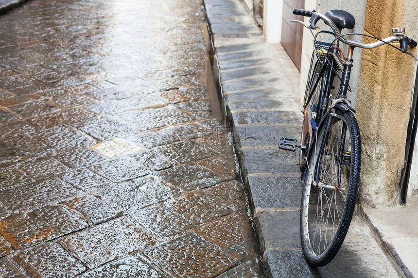 前往意大利在佛罗伦萨市湿街骑自行车秋天下雨图片