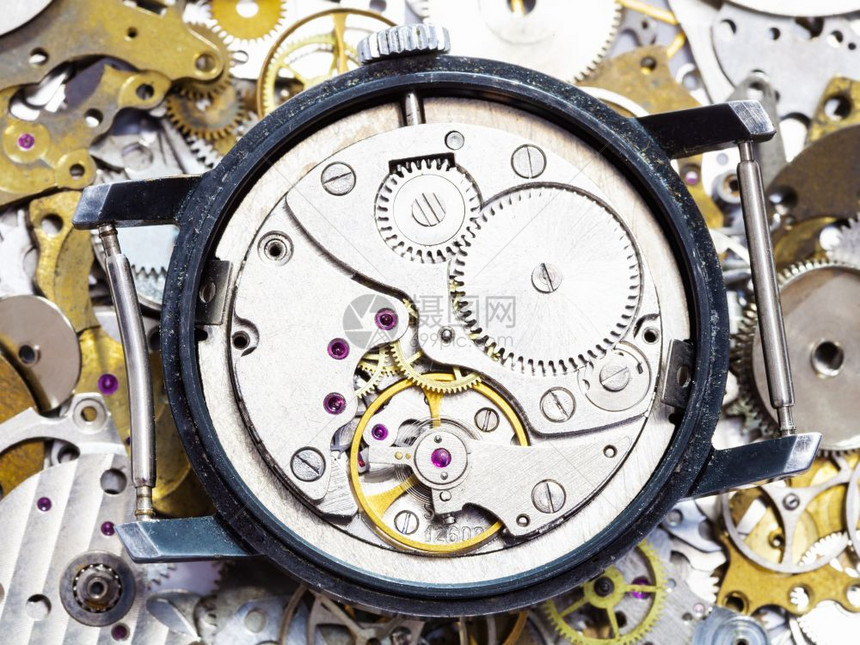 制表手在时钟备件堆上打开老式机械手表图片