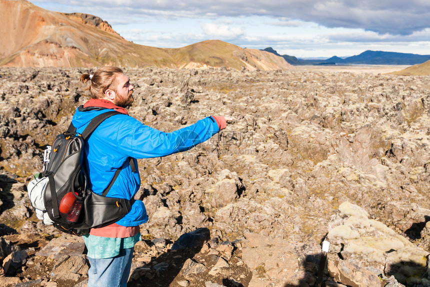 前往冰岛高地区Fjellabak自然保护区Landmannalaugar地区的Laugharaun火山熔岩场附近男子图片