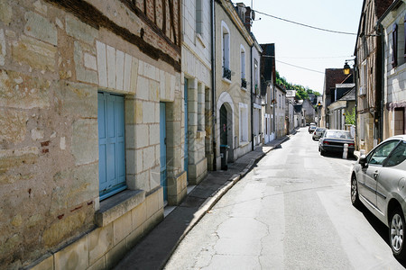 法国之旅阳光明媚的夏日卢瓦尔地区安布瓦兹镇维克托雨果街狭窄街道上的住宅和汽车背景图片