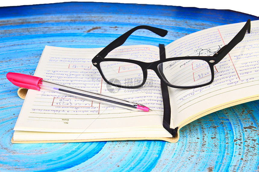 眼镜笔记本和放在桌上的功课图片