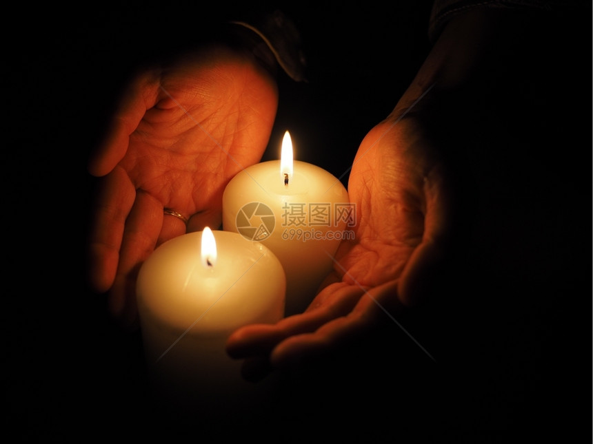 蜡烛和手放在黑色背景上图片