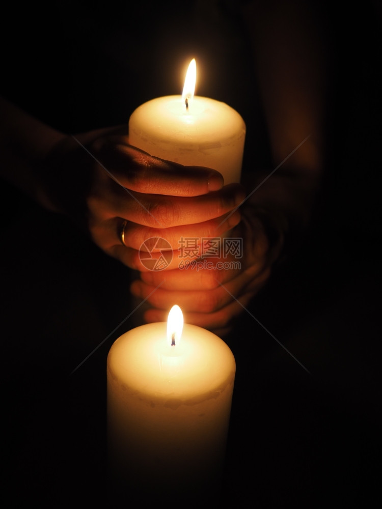 蜡烛和手放在黑色背景上图片