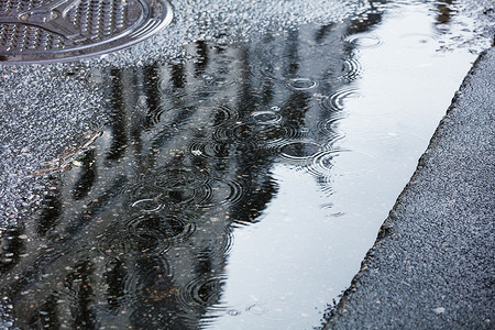 城里人行道上的雨水坑背景图片