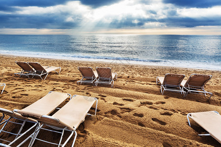 日出时沙滩上的甲板椅子图片