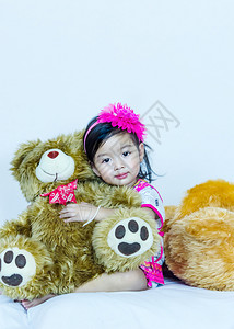 可爱的亚洲小女孩肖像拥抱她肥熊朋友室内拍摄可爱的亚洲小女孩肖像图片