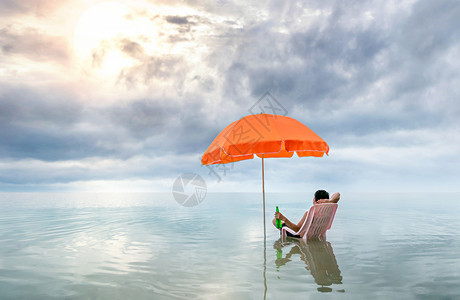 快乐的人坐在粉红休息椅上带着太阳伞坐在海中快乐的人坐在海中椅子上图片
