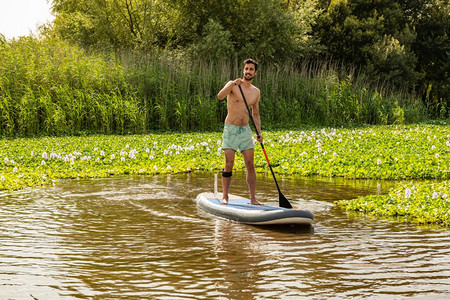 年轻人在湖边做水上运动男子在暑假时穿泳衣旅游图片