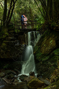 年轻夫妇在瀑布附近的自然双恋风景中享受孕期图片